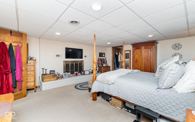 carpeted bedroom with a paneled ceiling and a fireplace