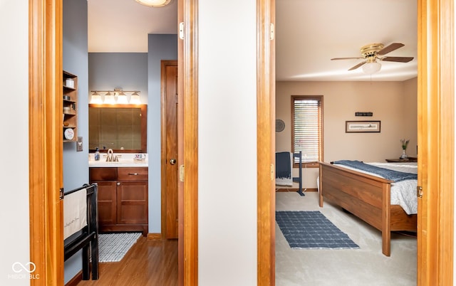 bedroom with light wood-type flooring, ceiling fan, and sink