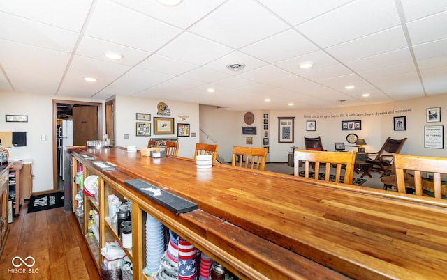 dining space featuring hardwood / wood-style flooring and a drop ceiling