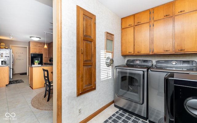 laundry room featuring washer and clothes dryer, light tile patterned floors, and cabinets