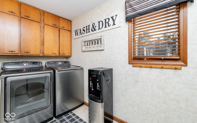 clothes washing area with washing machine and dryer, cabinets, and light tile patterned floors