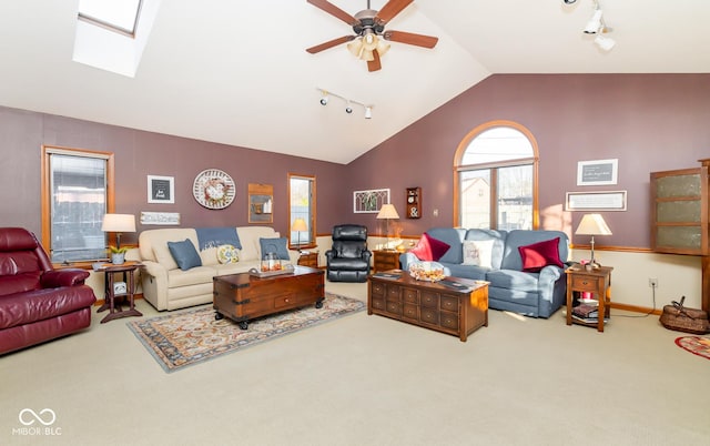 living room with lofted ceiling with skylight, rail lighting, carpet floors, and ceiling fan