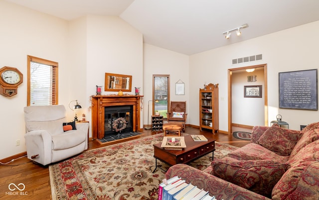 living room featuring vaulted ceiling, rail lighting, and hardwood / wood-style flooring