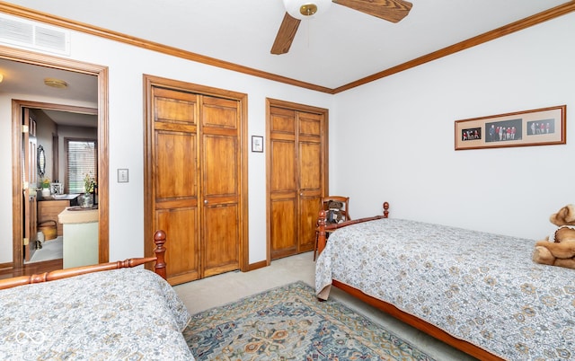 bedroom with light carpet, ceiling fan, crown molding, and two closets