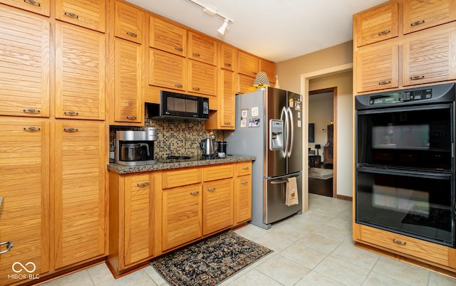 kitchen with light tile patterned floors, dark stone countertops, black appliances, and tasteful backsplash