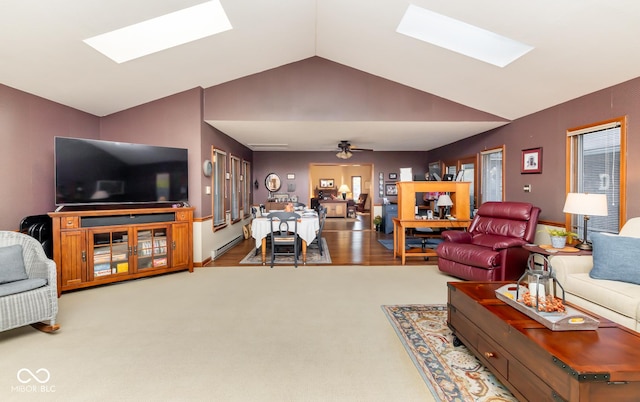 living room featuring ceiling fan, vaulted ceiling with skylight, and carpet flooring