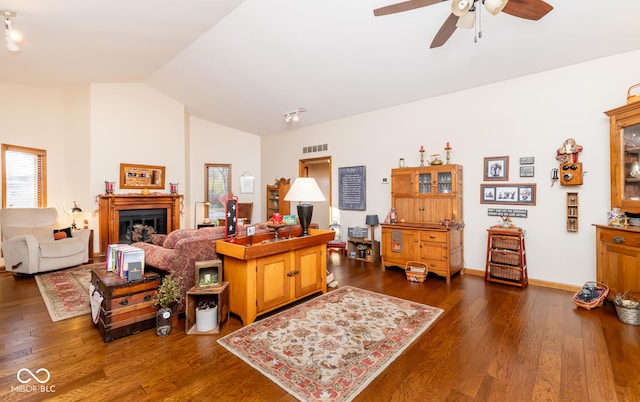 living room with ceiling fan, vaulted ceiling, and dark wood-type flooring