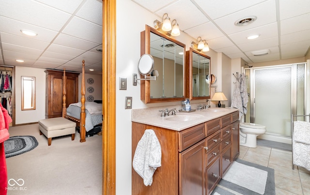 bathroom with a shower with door, a paneled ceiling, tile patterned floors, and vanity