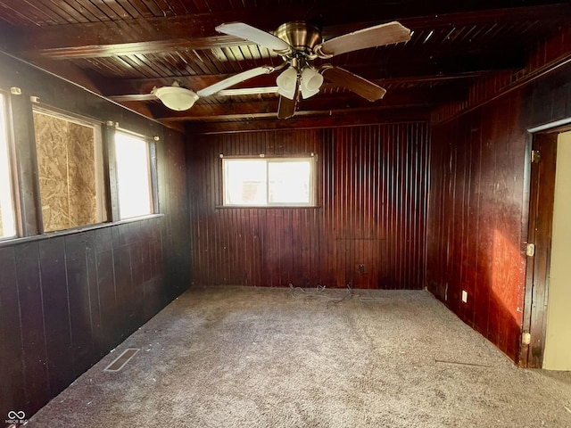 carpeted spare room with wood walls, plenty of natural light, beam ceiling, and wood ceiling