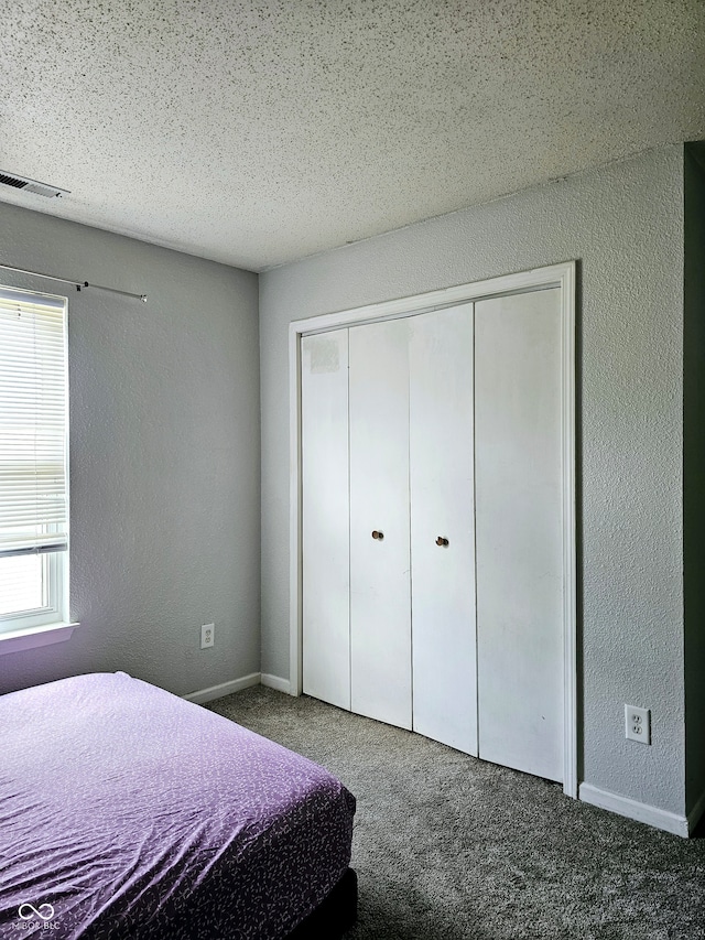 unfurnished bedroom with a closet, dark carpet, and a textured ceiling