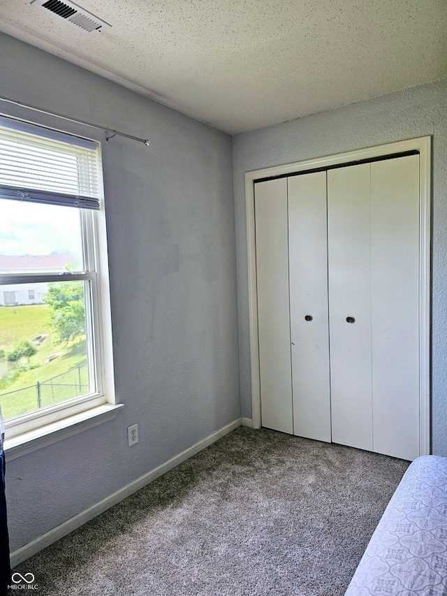 unfurnished bedroom with a closet, carpet floors, and a textured ceiling