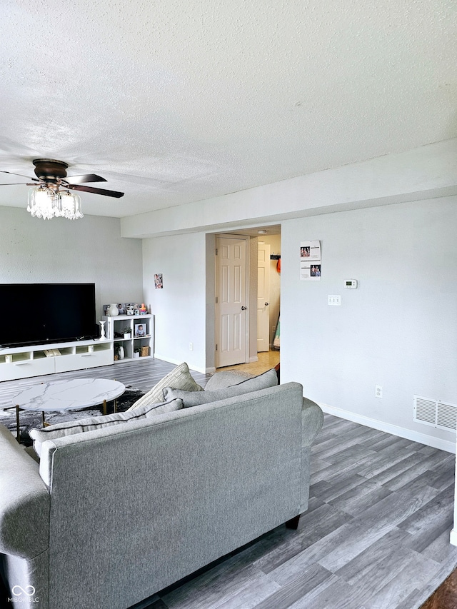 living room featuring ceiling fan, wood-type flooring, and a textured ceiling