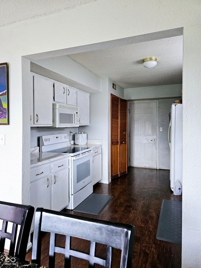 kitchen with a textured ceiling, white cabinetry, white appliances, and dark wood-type flooring