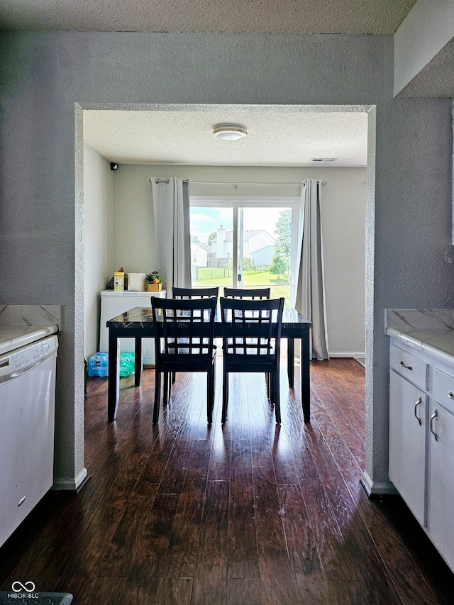 dining space with dark wood-type flooring and a textured ceiling