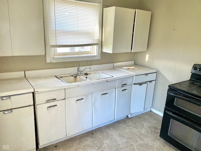 kitchen featuring white cabinetry, sink, and electric range