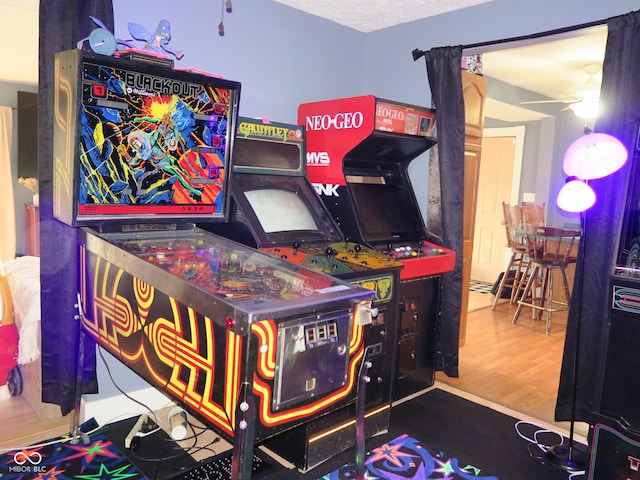 game room with hardwood / wood-style floors, ceiling fan, and a textured ceiling