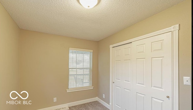 unfurnished bedroom with carpet flooring, a textured ceiling, and a closet