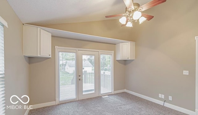 doorway with a textured ceiling, ceiling fan, light colored carpet, and vaulted ceiling