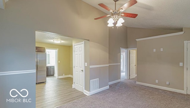 unfurnished room featuring a textured ceiling, ceiling fan, light carpet, and high vaulted ceiling