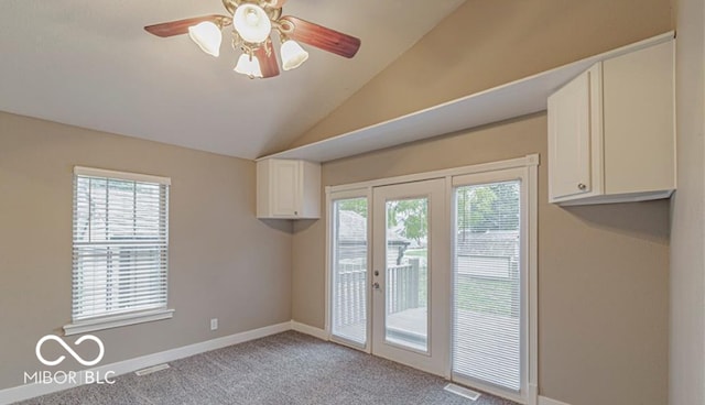 doorway to outside featuring light carpet, a wealth of natural light, lofted ceiling, and ceiling fan