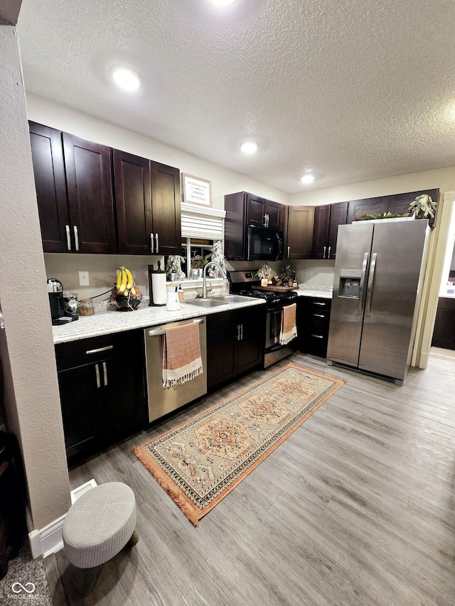 kitchen featuring black appliances, dark brown cabinetry, a textured ceiling, and light hardwood / wood-style flooring