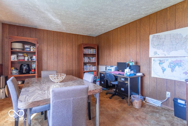 carpeted office space featuring a textured ceiling and wooden walls