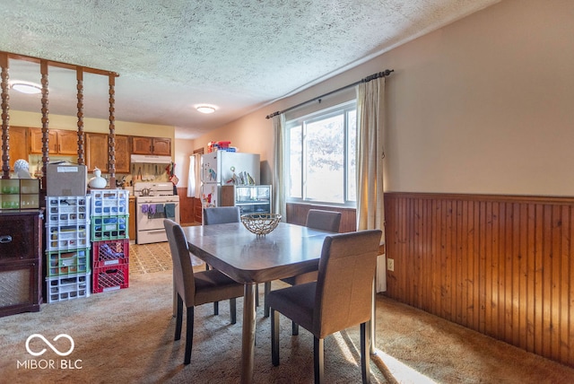 dining room featuring wooden walls, carpet floors, and a textured ceiling