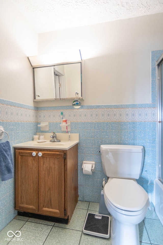 bathroom with tile patterned floors, vanity, toilet, and tile walls