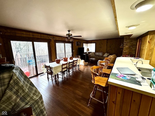 dining room with vaulted ceiling, wooden walls, ceiling fan, and dark hardwood / wood-style floors