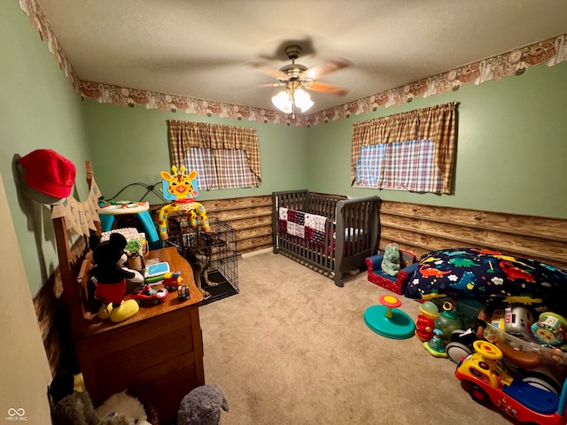 carpeted bedroom with ceiling fan and a crib