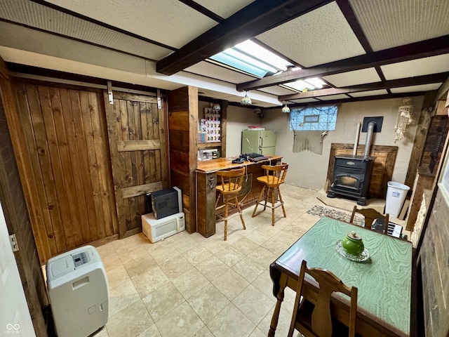 home office with light tile patterned flooring, a wood stove, and wooden walls