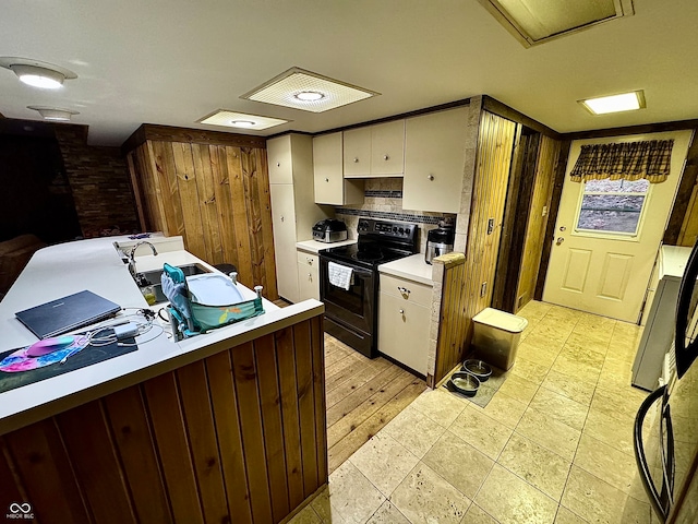 kitchen with electric range, light hardwood / wood-style floors, and white cabinetry