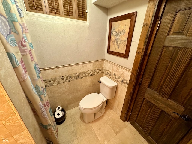 bathroom with toilet and tile walls