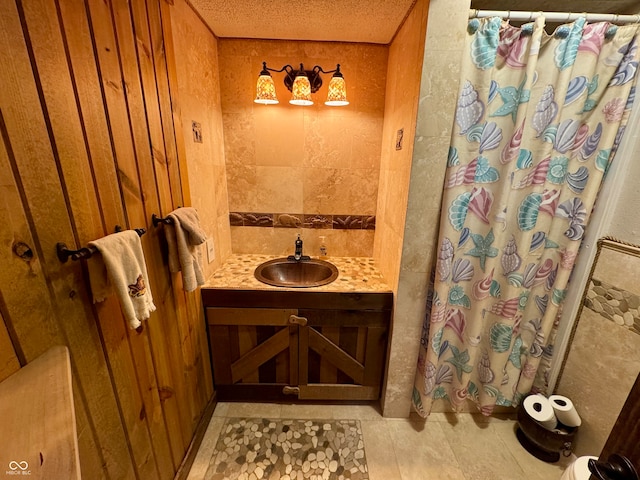 bathroom featuring curtained shower, tile patterned floors, a textured ceiling, wooden walls, and vanity