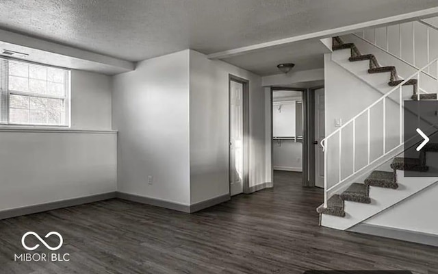 basement featuring a textured ceiling and dark hardwood / wood-style floors