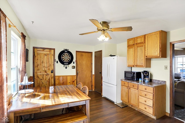 kitchen with white refrigerator, dark hardwood / wood-style floors, ceiling fan, and wooden walls