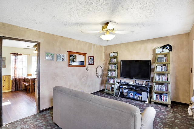 living room featuring ceiling fan, dark wood-type flooring, and a textured ceiling