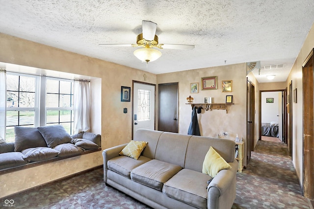 living room with dark colored carpet, a textured ceiling, and ceiling fan