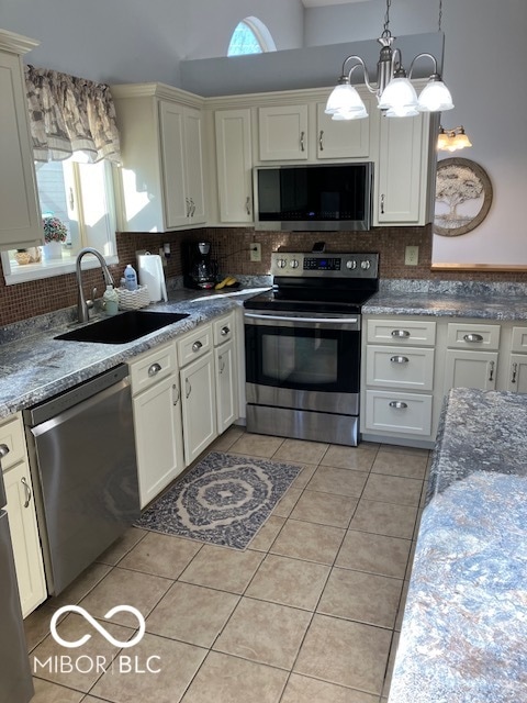 kitchen with decorative backsplash, hanging light fixtures, stainless steel appliances, and sink