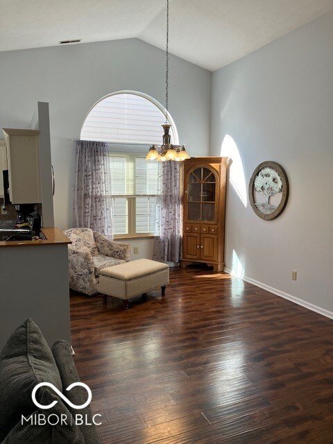 living room with sink, dark hardwood / wood-style flooring, lofted ceiling, and a notable chandelier