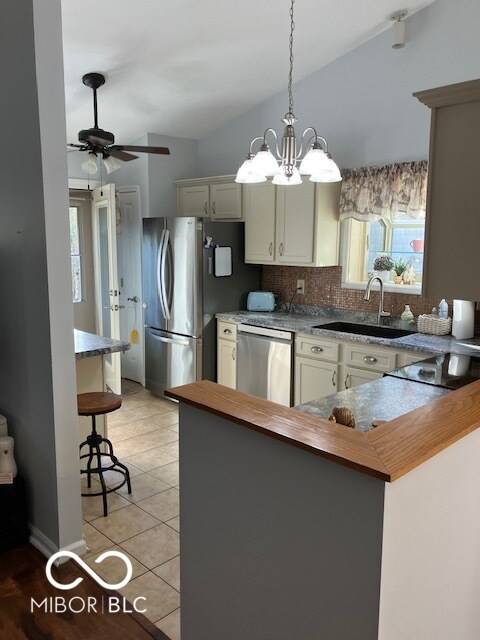 kitchen with sink, stainless steel appliances, backsplash, kitchen peninsula, and ceiling fan with notable chandelier