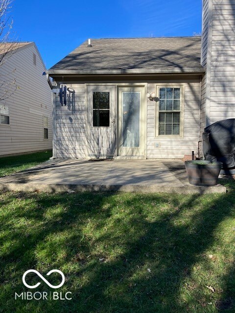 rear view of house with a lawn and a patio