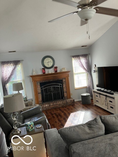 living room featuring dark hardwood / wood-style flooring, a fireplace, a healthy amount of sunlight, and lofted ceiling