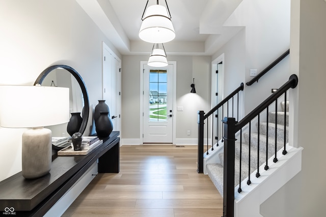 entryway with a raised ceiling and light wood-type flooring