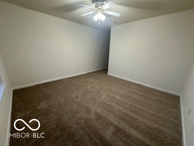 spare room featuring ceiling fan, dark carpet, and a textured ceiling