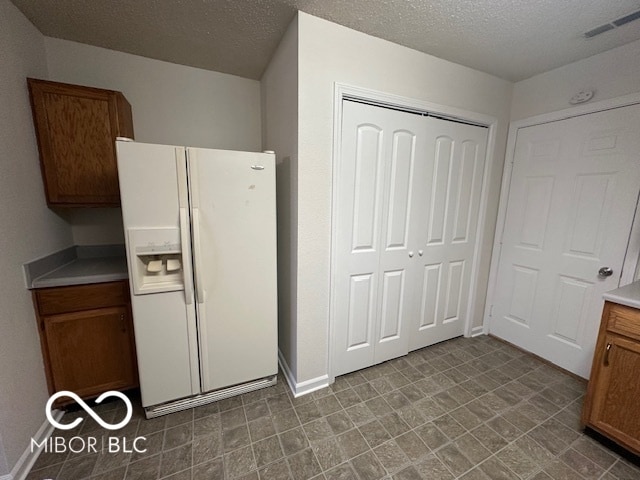 kitchen with white fridge with ice dispenser and a textured ceiling