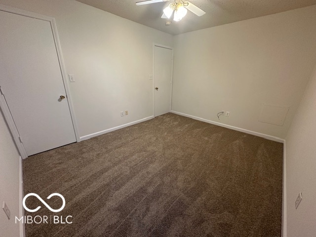 empty room featuring dark colored carpet and ceiling fan