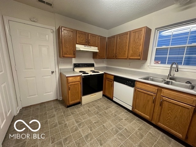 kitchen with a textured ceiling, white appliances, and sink