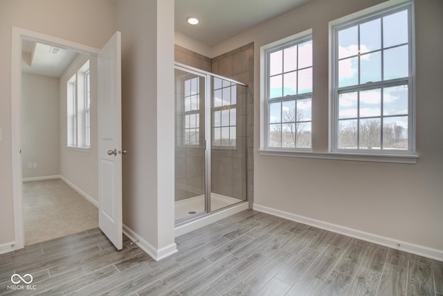 bathroom with a shower with door and wood-type flooring