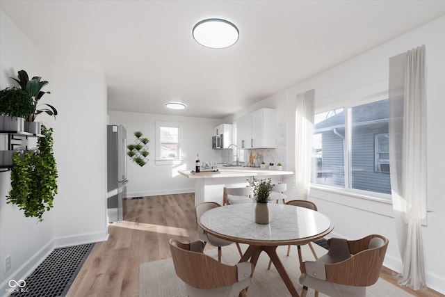 dining space featuring light wood-type flooring and sink